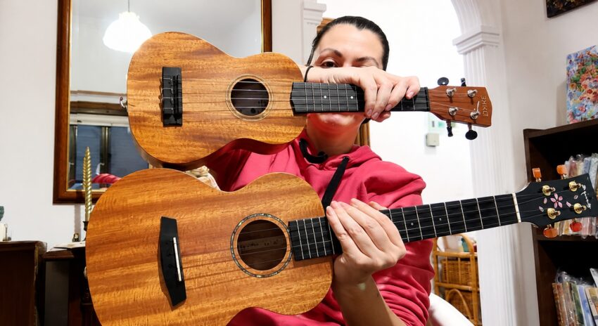 Woman holding a soprano and tenor ukulele indoors